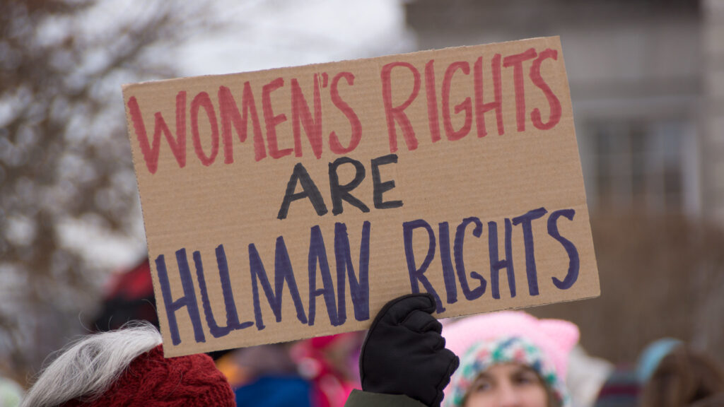 Photo of rally for women's rights with person holding a sign that reads, "women's rights are human rights"