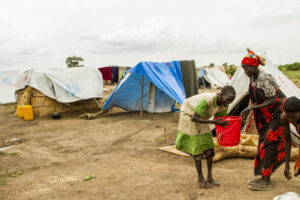 Millions live within camps in Ethiopia, woman with water bucket in front of tents in a camp in Ethiopia